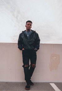 Portrait of young man standing against wall