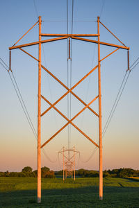 Low angle view of electricity pylon on field against clear sky