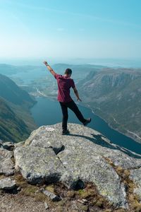 Full length of man balancing on rock against mountains and sky