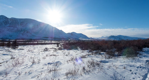 Scenic view of frozen lake by snowcapped mountains against sky