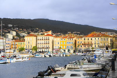 Sailboats moored in harbor by town against sky