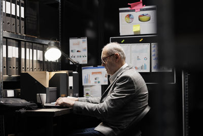 Side view of businessman using laptop at office