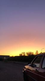 Cars on road against clear sky at sunset