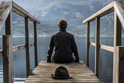 Rear view of man sitting on jetty