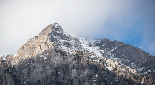Snow covered rock mountain against sky
