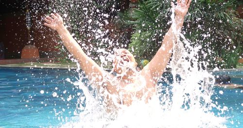 Man splashing water in swimming pool