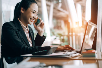 Young woman using mobile phone while sitting on table