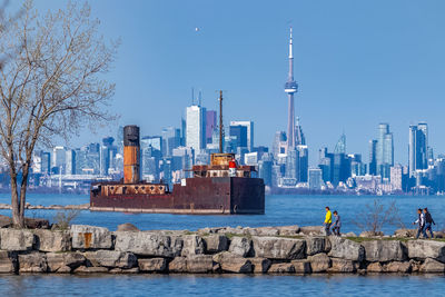 Abandoned boat in sea against cityscape