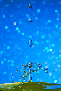 Low angle view of raindrops falling in blue water