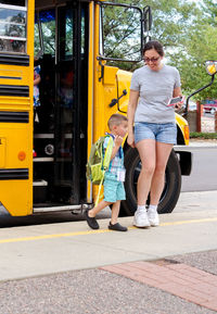 Mom meets her young child getting off a school bus