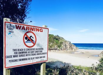 Information sign on beach against sky