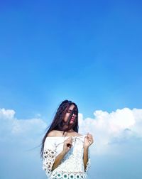 Low angle view of woman standing against blue sky