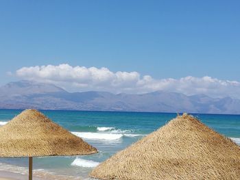 Deck chairs on beach against sky