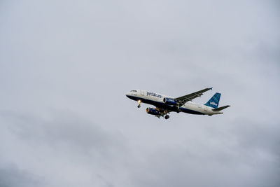 Low angle view of airplane flying against sky