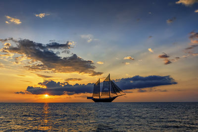 Sailboat in sea against sky during sunset