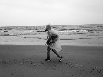 Rear view of woman standing on beach against clear sky