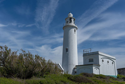 Low angle view of lighthouse by building against sky