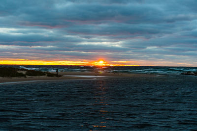 Scenic view of sea against dramatic sky during sunset