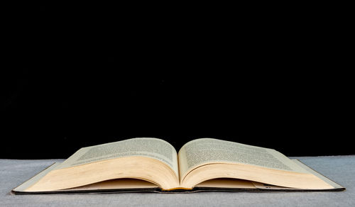 Open book on table against black background