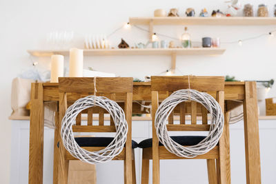 Wooden kitchen chairs decorated with christmas wreaths in scandinavian cuisine