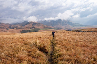 Front view of woman hiking on path with mountain against sky in the background 