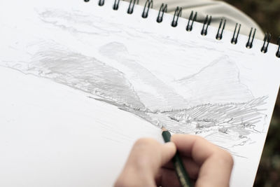 Cropped image of person sketching on paper