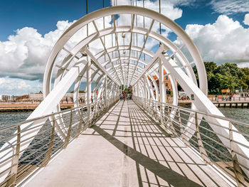 View of footbridge in city against cloudy sky