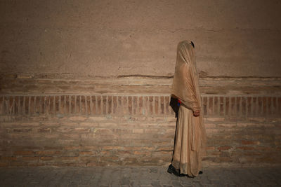 Side view of woman standing against wall