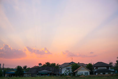 Houses and trees against sky during sunset