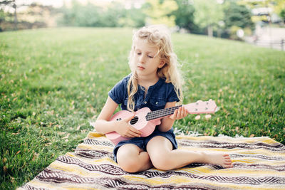 Full length of girl sitting on field