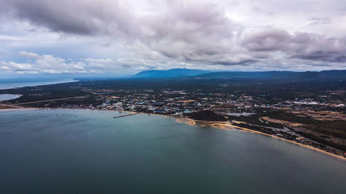 Aerial view of city by sea against sky