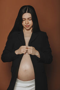 Portrait of woman standing against yellow background