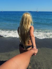 Rear view of woman standing at beach against clear sky