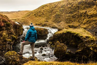 Rear view of man standing in front of waterfall