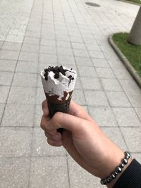 Midsection of person holding ice cream on footpath