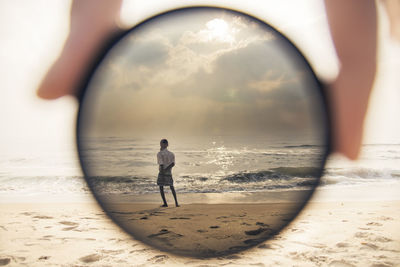 Rear view of man on beach against sky