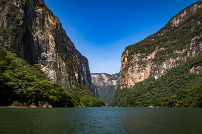 Scenic view of sea and mountains against blue sky