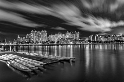 Panoramic view of illuminated buildings by sea against sky at night