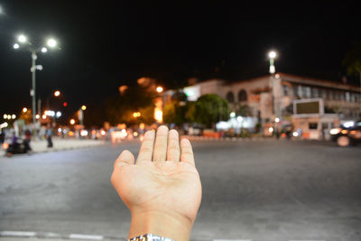 Close-up of human hand against illuminated building