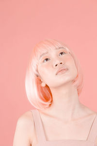 Close-up portrait of young woman against gray background