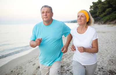 Mature couple jogging on shore at beach