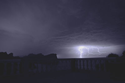 Silhouette of illuminated building against sky at night