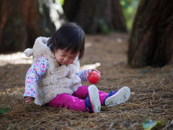 Full length of cute baby girl sitting on twigs at park