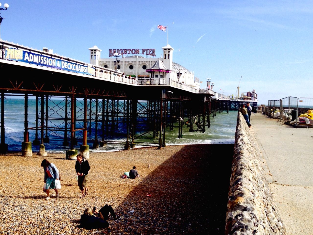 built structure, architecture, building exterior, beach, large group of people, person, men, clear sky, water, lifestyles, sunlight, sea, leisure activity, sky, incidental people, sand, day, walking, shadow