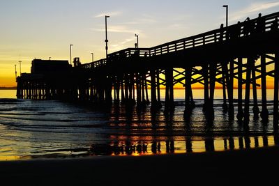 Silhouette pier over sea against sky during sunset