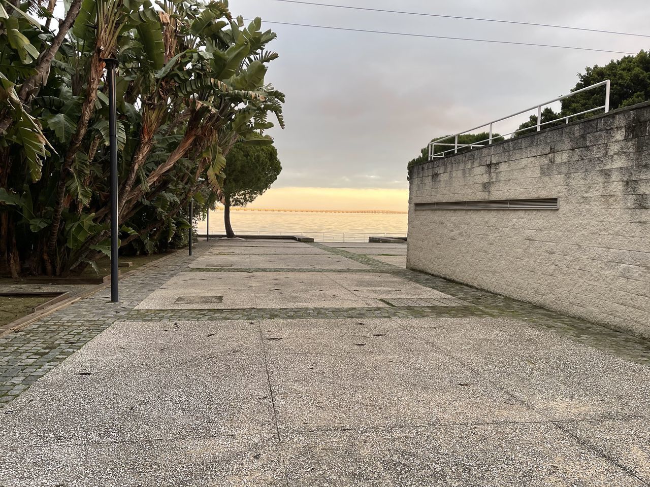 FOOTPATH BY SEA AGAINST SKY DURING SUNSET