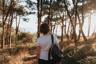 Rear view of woman standing in forest