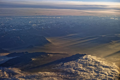 Aerial view of dramatic landscape against sky during sunset