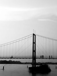 Suspension bridge over sea against sky