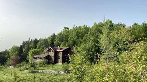 Built structure on field by trees against sky